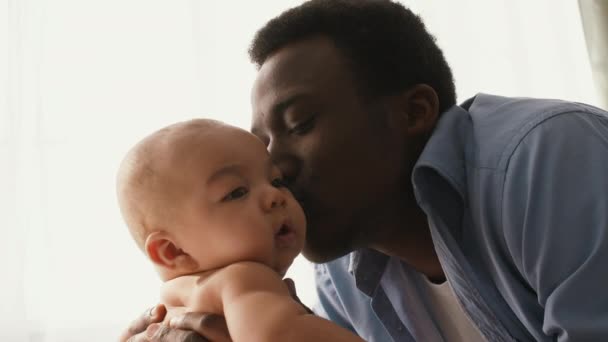 Close-up portret van Afrikaanse Amerikaanse vader spelen met zijn schattige pasgeboren baby, genieten van zijn vaderschap — Stockvideo