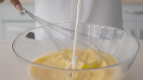 Recept på äggröra. Närbild skott av kock hälla mjölk och blanda ägg med visp i köket, slow motion — Stockvideo