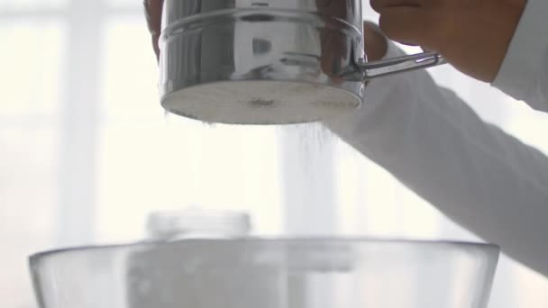 Närbild skott av kock konfektyr lägga mjöl till skålen med rostfritt mjöl sifter, med hjälp av bakverk på disken — Stockvideo