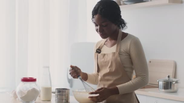 Щаслива африканська американка, яка змішує тісто з домашньої пекарні, готує тістечко тільки вдома на кухні. — стокове відео