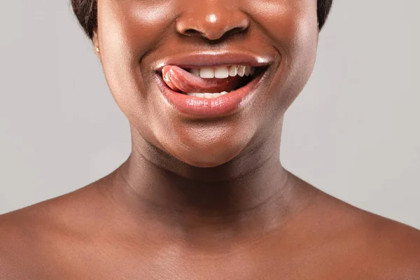 Обрізаний образ гола чорна жінка грайливо кусає її язик і посміхається — стокове фото