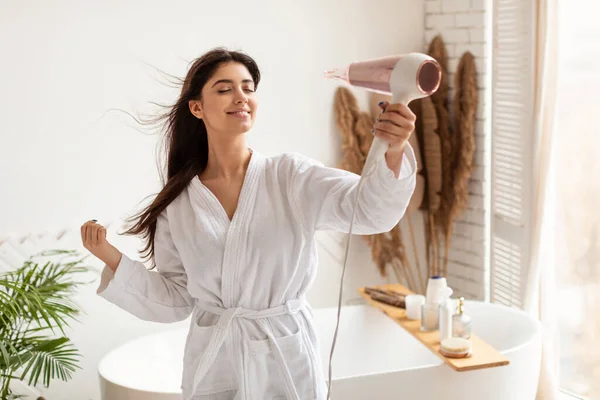 Brunette vrouw drogen en styling haar met haardroger in de badkamer — Stockfoto