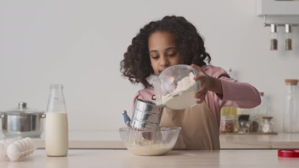 Carina ragazza afroamericana che aggiunge farina alla ciotola, prepara la pasta per la pasticceria fatta in casa, cucina panificio in cucina — Video Stock