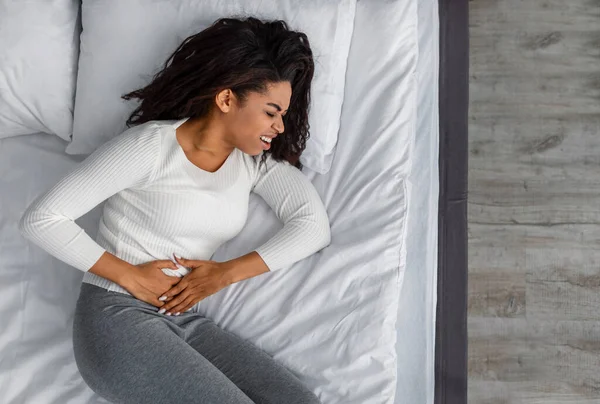 Zwarte vrouw die lijdt aan buikpijn, aanraken van haar buik — Stockfoto