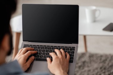 Tanımlanamayan erkek serbest çalışan boş ekranlı dizüstü bilgisayar kullanan, online çalışan ve internet sitesi reklamcısı