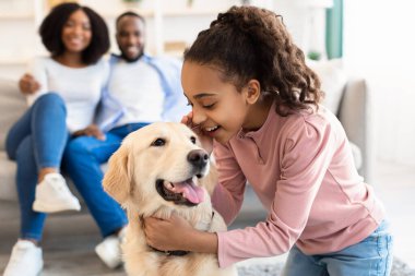 Genç siyah kız köpekle sarılıyor ve fısıldıyor.