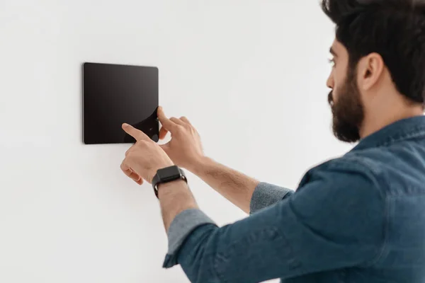 Tecnología innovadora para apartamentos. Chico usando tableta digital en la pared con la aplicación del sistema de control del hogar inteligente —  Fotos de Stock