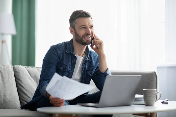 Glücklicher Geschäftsmann, der mit Dokumenten arbeitet, mit Kunden per Smartphone spricht — Stockfoto