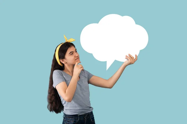 Pensive indický dospívající dívka drží prázdný řeč bublina s kopírovat prostor pro váš text na modrém pozadí studia — Stock fotografie