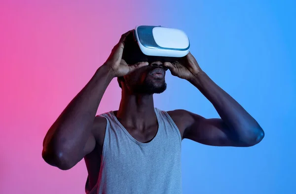 Спортсмен чорний хлопець в гарнітурі VR, робить віртуальні тренування в доповненій реальності, неонове освітлення — стокове фото