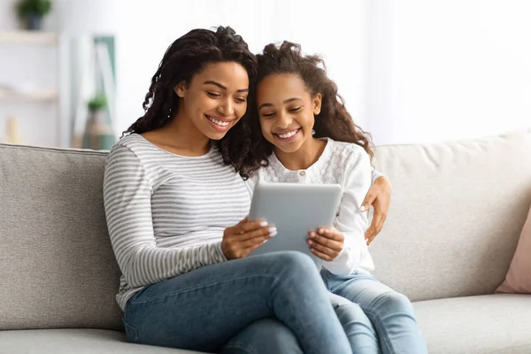 Mutlu Afro-Amerikan annesi ve çocuğu dijital tablet kullanıyorlar.