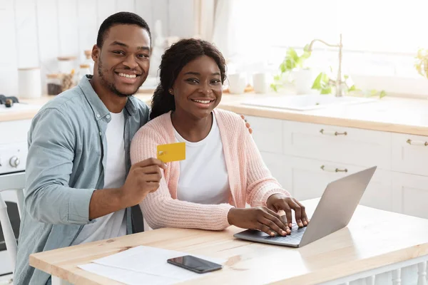 Pagamenti online. Ritratto di giovani sposi africani con computer portatile e carta di credito — Foto Stock