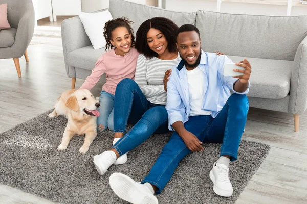 Joven familia negra tomando selfie con perro en casa — Foto de Stock