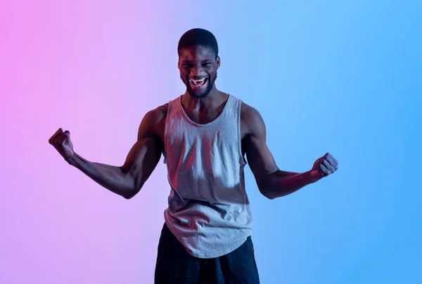 Retrato de jovem atleta negro gesticulando SIM, celebrando vitória ou realização esportiva em luz de néon — Fotografia de Stock
