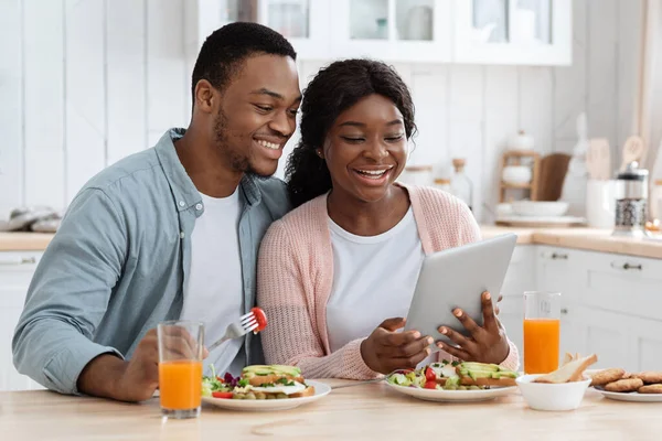 Shopping en ligne. Millennial couple noir dans la cuisine en utilisant la tablette numérique pendant le petit déjeuner — Photo