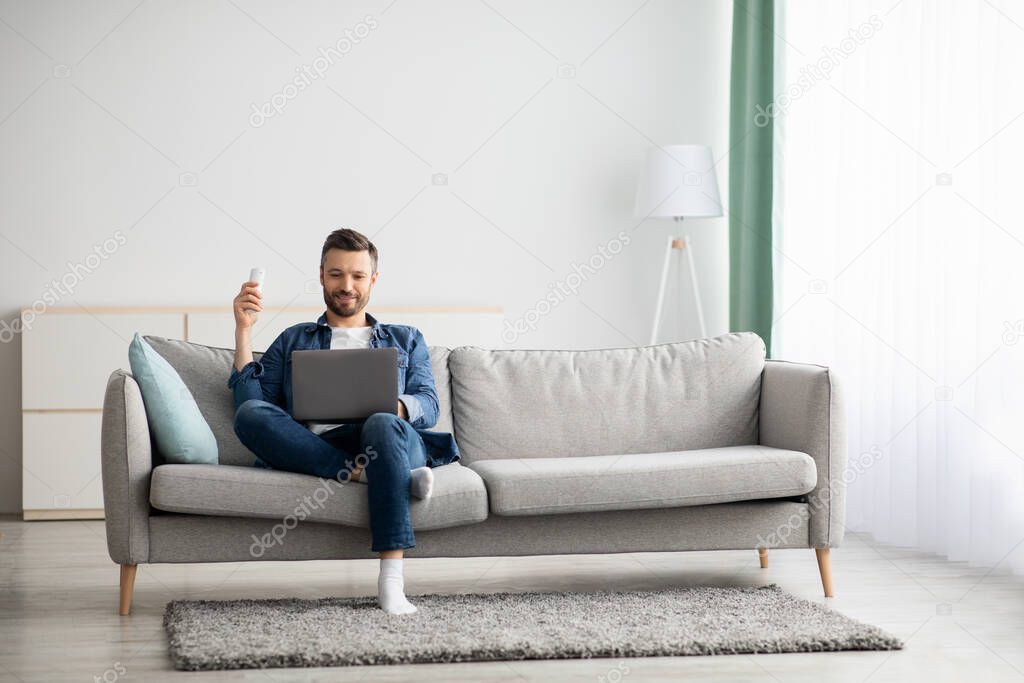Relaxed man with laptop sitting on couch at home