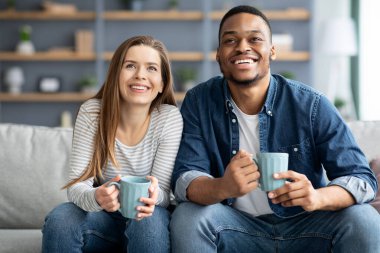 Hafta sonu tatili. Neşeli, genç, çok kültürlü bir çift oturma odasında dinleniyor.