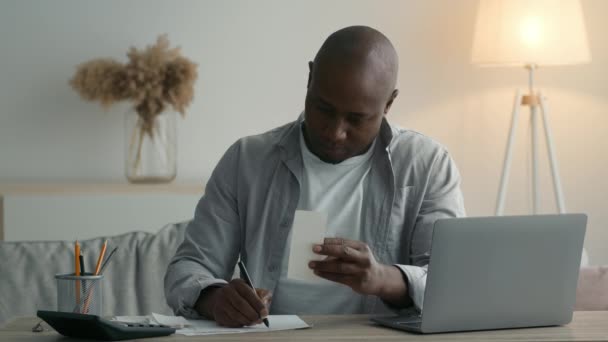 African American Businessman Holding Financial Bill Taking Notes At Home — Stockvideo