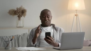 Cheerful African American Man Using Phone Reading Message Sitting Indoors