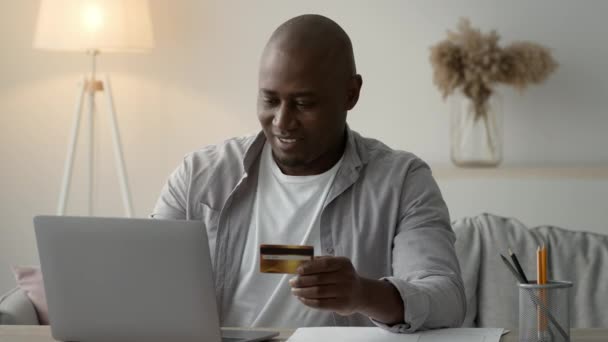 African American Man Using Laptop And Credit Card At Home — Stockvideo