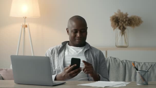 Displeased Black Man Using Smartphone Scrolling Negative News Sitting Indoors — Wideo stockowe