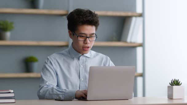 Kutu buku Asia muda mengenakan kacamata membaca pesan dengan berita besar dan menikmati prestasi, bekerja di kantor pusat — Stok Video