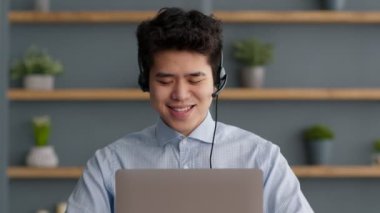 Online eğitim. Kulaklık takan Asyalı öğrenci hocasıyla sohbet ediyor, bilgisayardan yabancı dil öğreniyor.