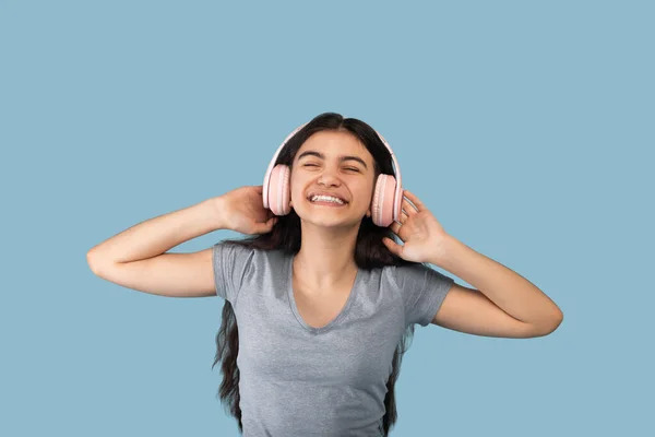 Adolescente indio feliz en auriculares inalámbricos modernos disfrutando de la canción popular en la aplicación de audio, escuchando música —  Fotos de Stock