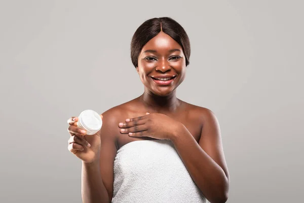 Nutrição da pele. Jovem mulher afro-americana atraente segurando frasco com creme hidratante — Fotografia de Stock