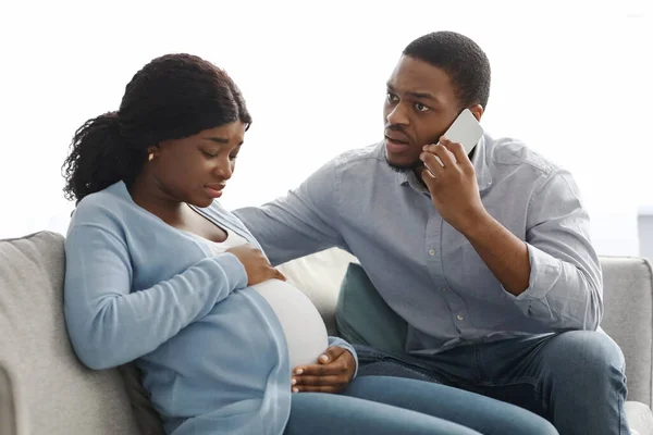 Figyelmes fekete férj hívja orvos, míg a feleség, amelynek szülési fájdalmak — Stock Fotó
