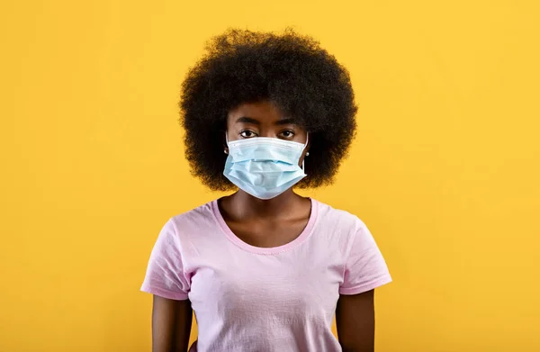 感染和保护概念。戴医疗面具的非洲裔美国女青年，背景是黄色的 — 图库照片
