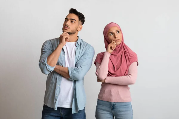 Difícil elección. Retrato de pareja árabe pensativa de pie sobre fondo gris —  Fotos de Stock