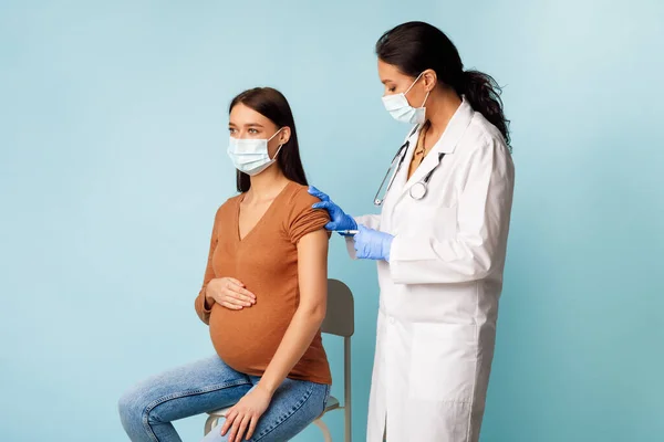 Wanita muda hamil Mendapatkan Vaksinasi Untuk Pencegahan Kovid-19, Latar Belakang Biru — Stok Foto