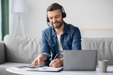 Evden online eğitime katılan orta yaşlı pozitif bir adam.