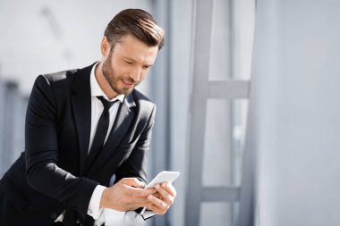 Gülümseyen işadamı ayrılmayı beklerken sevgilisine mesaj atıyor.