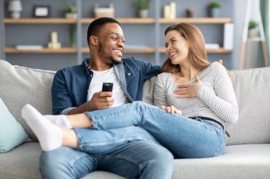 Romantik, genç, çok ırklı çift koltukta dinleniyor ve sohbet ediyorlar.