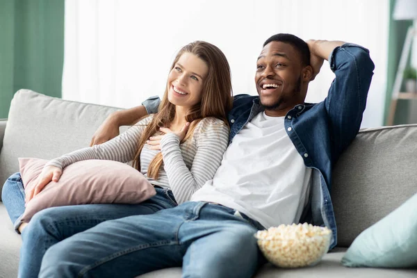 快乐的多种族伴侣看电视和在家里放松沙发 — 图库照片