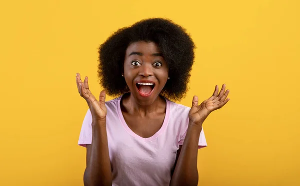 Inacreditável. Mulher afro-americana chocada gritando com a boca aberta, olhando para a câmera sobre fundo amarelo — Fotografia de Stock