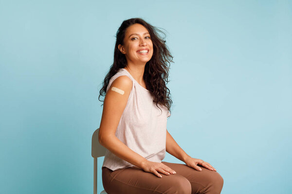 Joyful Female Showing Vaccinated Arm Over Blue Background In Studio