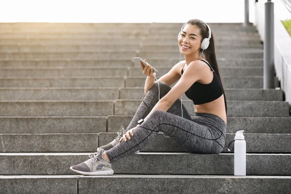 Chica asiática escuchando música en el Smartphone, Descansando después del entrenamiento de fitness en el parque — Foto de Stock