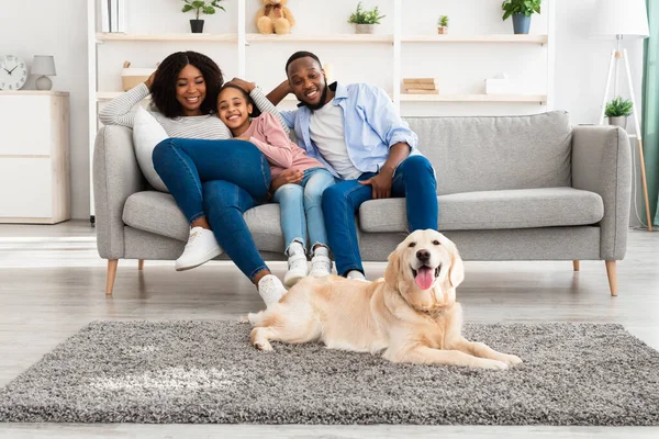 Feliz família negra sentada na sala de estar com cão — Fotografia de Stock