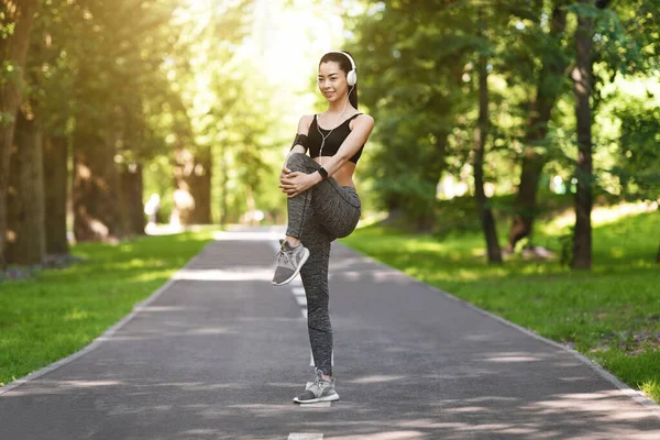 Ajuste coreano chica en ropa deportiva ejercicio al aire libre y escuchar música en los auriculares — Foto de Stock