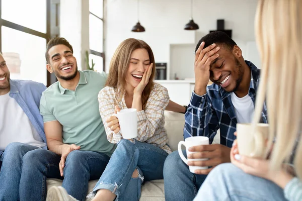 Ha kul med vänner. Grupp unga multiraser som dricker kaffe hemma, skämtar och skrattar tillsammans — Stockfoto