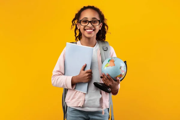 Весела молода чорна дівчина тримає земну кулю і блокнот — стокове фото