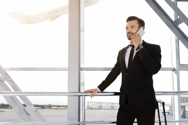 Homme d'affaires joyeux debout à l'aéroport, parlant au téléphone — Photo