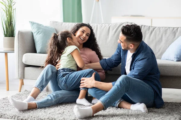 Concepto de seguro familiar. Retrato de alegres padres jóvenes y su hijita — Foto de Stock