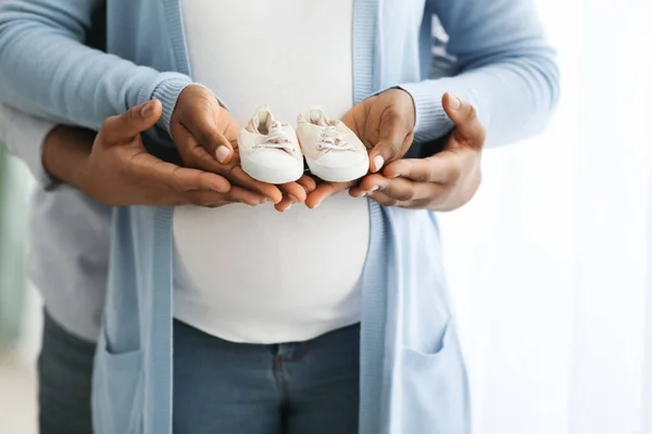 Cropped of pregnant african american family holding small baby shoes — Stock Photo, Image