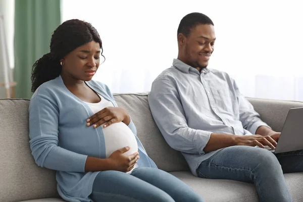 Mulher africana grávida perturbada sentada ao lado do marido usando laptop — Fotografia de Stock