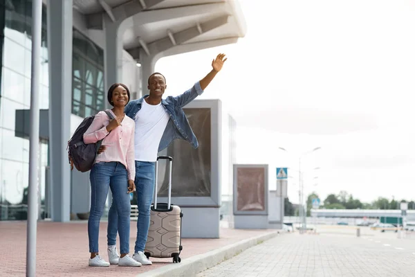 공항 터미널 근처에서 택시 를 타고 있는 행복 한 젊은 흑인 부부 — 스톡 사진