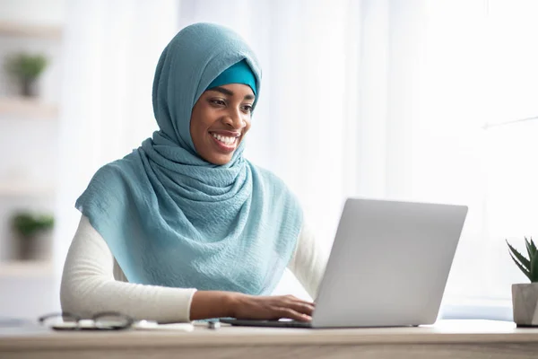 Retrato de mulher islâmica negra no Hijab trabalhando no laptop no escritório — Fotografia de Stock